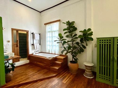 a bathroom with a bath tub and a potted plant at The Apsara in Luang Prabang
