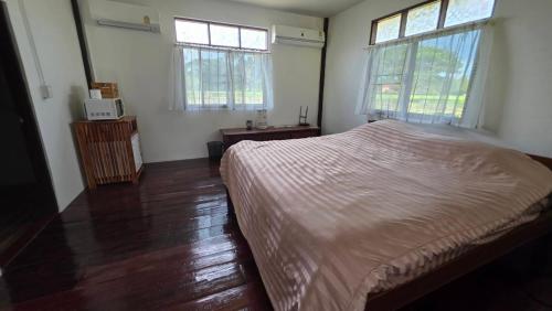 a bedroom with a bed and two windows at DGD Chiangmai in Mae Rim
