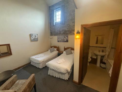 a small room with two beds and a sink at The White Lion Hotel in Bridgend