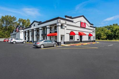 a large white building with cars parked in a parking lot at Red Carpet Inn and Suites in Bellmawr