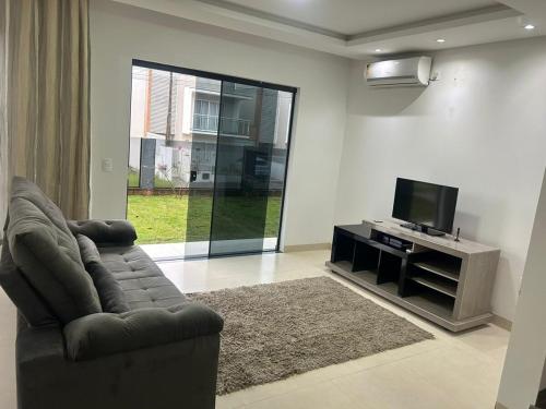 Una sala de estar con un sofá y un televisor de pantalla plana. en Pousada Ypê, en São Lourenço do Oeste