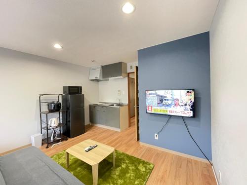 a living room with a couch and a tv on a wall at アムホテル in Tokyo