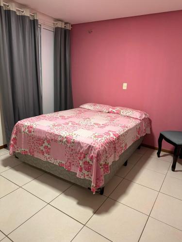 a bed in a room with a pink wall at Apartamento Térreo no Catu Lake Resort Aquiraz in Aquiraz