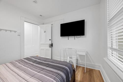 a bedroom with a bed and a tv on a wall at Pittsburgh Shadyside 2D Modern and Stylish Private Bedroom with Shared Bathroom in Pittsburgh