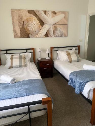 Dos camas en una habitación con un cuadro en la pared. en Spacious Williamstown Apartment with Free Parking, en Williamstown