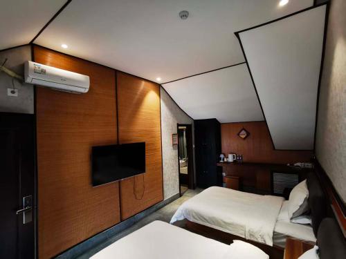 Una pequeña habitación con dos camas y un televisor. en Zhifang Hotel, en Datong