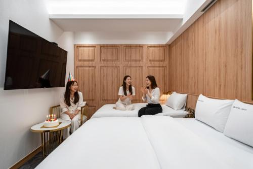 three women sitting on a bed in a hotel room at HotelInsta Main Branch in Suwon