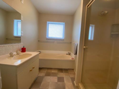 a bathroom with a tub and a sink and a mirror at 8b Rippingale Road in Hanmer Springs