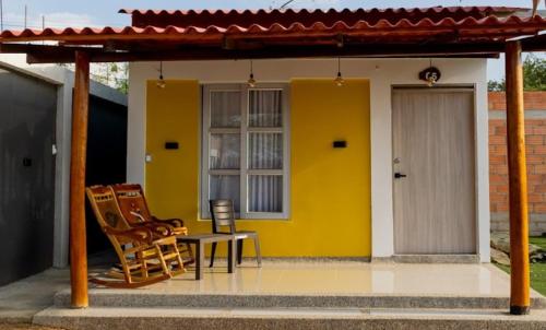 a yellow house with two chairs and a table at Hotel Alikaa Wayira in Ríohacha