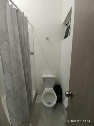 a bathroom with a toilet and a shower curtain at posada ah mun centro in Mérida