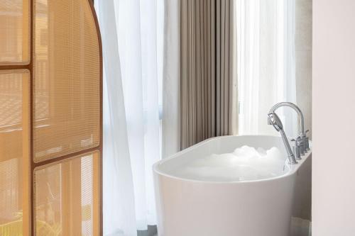 a bath tub sitting in front of a window at Guilin Camphor Country House Free pick-up service at train station for two nights in Guilin