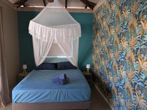 1 dormitorio con 1 cama azul con dosel en Vaiava Lodge, en Punaauia