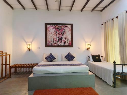 a bedroom with two beds and a painting on the wall at Jungle Baum Villa Habarana in Hiriwadunna