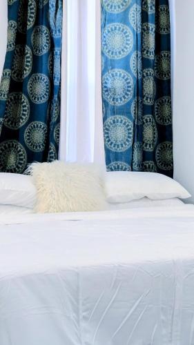 a bed with a white pillow and a blue curtain at Luxury 2bedrooms 1bath home near philly museum Temple and center city in Philadelphia