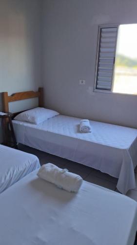 three beds in a room with a window at Pousada Serra Azul in Juquiá