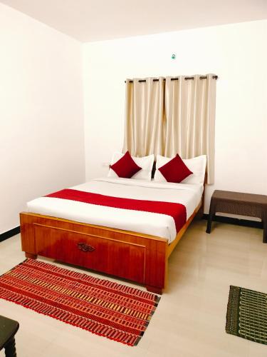 ein Schlafzimmer mit einem Bett mit roten Kissen in der Unterkunft Harvest Hill View Cottage in Udagamandalam