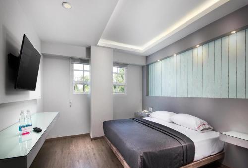 a bedroom with a bed and a desk and windows at Hotel MX congreso CDMX, Trademark Collection by Wyndham in Mexico City