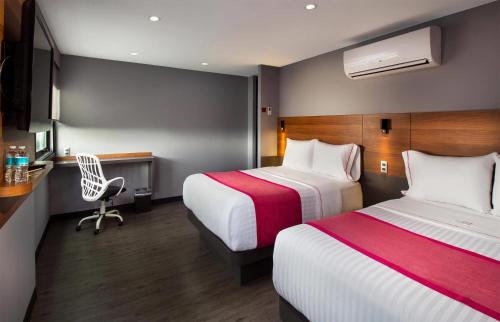 a hotel room with two beds and a desk at Hotel MX aeropuerto CDMX, Trademark Collection by Wyndham in Mexico City