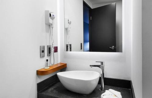 a bathroom with a white sink and a mirror at Hotel MX aeropuerto CDMX, Trademark Collection by Wyndham in Mexico City
