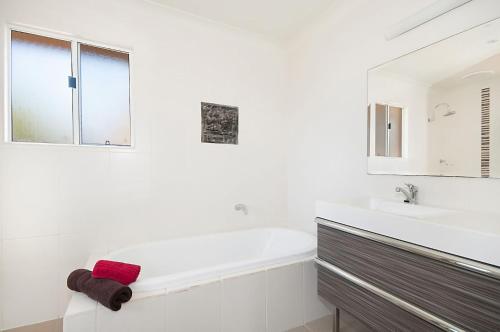a white bathroom with a tub and a sink at Waitui 1 - 3 Somerset Street in Byron Bay
