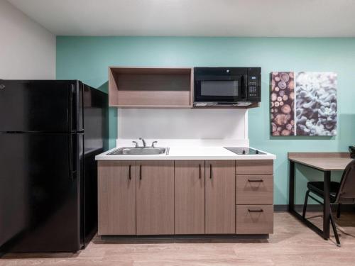 a kitchen with a sink and a black refrigerator at ECHO Suites Extended Stay by Wyndham Springfield Airport PLZ in Springfield
