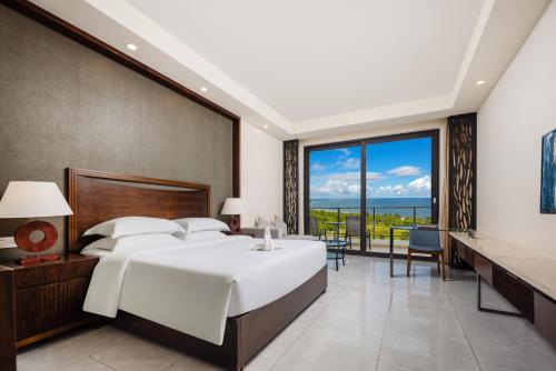 a bedroom with a large white bed and a large window at Boao Holliyard hotel in Qionghai
