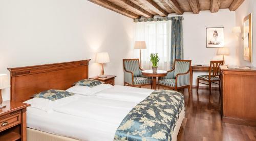 a bedroom with a bed and a desk and chairs at Hotel Restaurant Lilie in Vipiteno