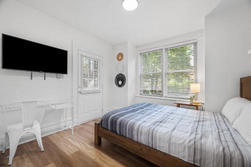 a bedroom with a bed and a desk and a flat screen tv at Pittsburgh Shadyside 2E Bright Modern Private Bedroom with Shared Bathroom in Pittsburgh