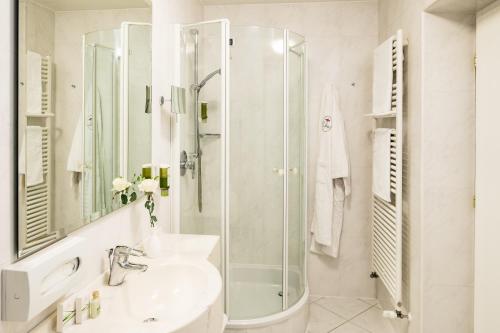 a white bathroom with a shower and a sink at Hotel Restaurant Lilie in Vipiteno