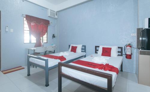 a room with two beds with red pillows at RedDoorz Plus near Tambo Paranaque in Manila