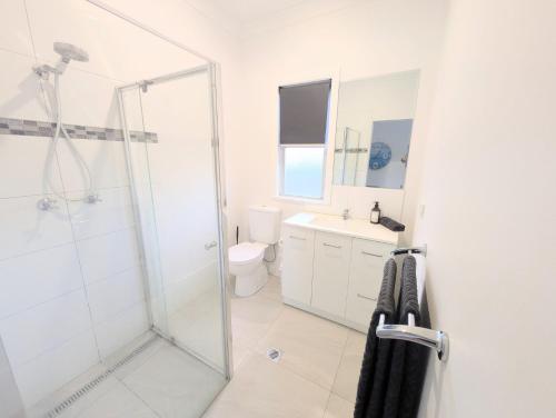 Un baño blanco con ducha y WC. en Blue Palms Cottage, en North Haven