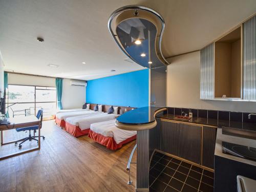a hotel room with a bed and a desk and a kitchen at ライカムファミリーリゾートホテル旧HiyagunLanaiResort in Okinawa City