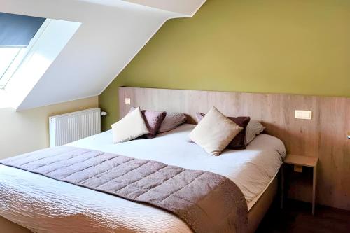 a bedroom with a large bed with pillows on it at Hotel des Postes in Houffalize