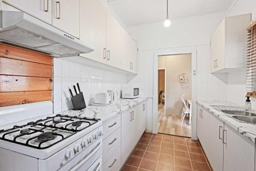 a white kitchen with a stove and a sink at Boutique Double Room - Centrally Located at Granville - Shared Bathroom in Sydney
