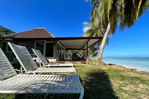 a group of chairs sitting on the grass near the ocean at Fare Matairoa - 2BR Beach Cottage in Iumaru
