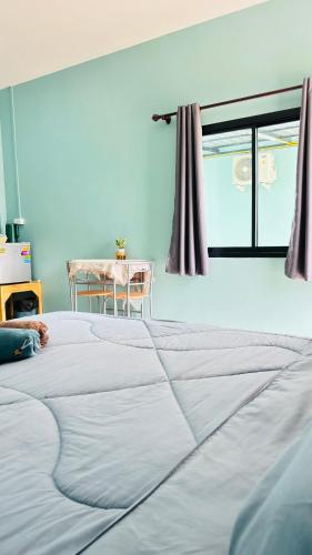 a large white bed in a room with a table at เอ็นแอนด์พี รีสอร์ทบุรีรัมย์ in Ban Don Wai