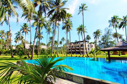 een zwembad met palmbomen en een gebouw bij Chang Noi Paradise Apartments in Ko Chang