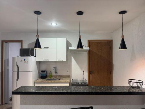 une cuisine avec des armoires blanches et un réfrigérateur blanc dans l'établissement Apartamento aconchegante na Praia de Piratininga em Niterói, à Niterói