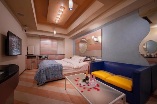 a bedroom with a bed and a couch and a table at Hotel Grand Garden (Adult Only) in Yokohama