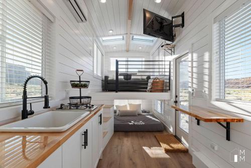 a kitchen with a sink and a tv and windows at Tiny Home Lodge Near Zion National Park Breathtaking Views in Apple Valley