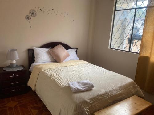 a bedroom with a bed with a pillow and a window at Residencia Lolita, tu hogar en Loja in Loja