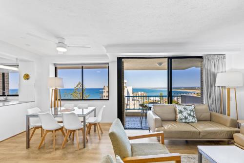 a living room with a couch and a table and chairs at Burgess @ Kings Beach Apartments in Caloundra