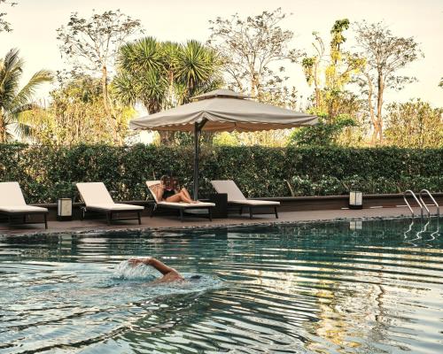 a person swimming in a pool with an umbrella at Kobi Onsen Resort Hue, Affiliated by Melia in Hue