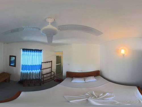 a bedroom with a large white bed and a window at Asanka Surf House & Restauranys in Midigama
