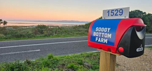 a gas pump sign on the side of a road at Soggy Bottom Farm House, Sea views and peacocks in Pakawau