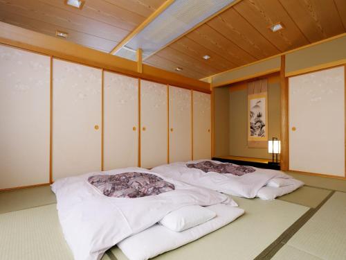 two beds in a room with wooden ceilings and windows at Kanko Hotel Tamaru in Nara