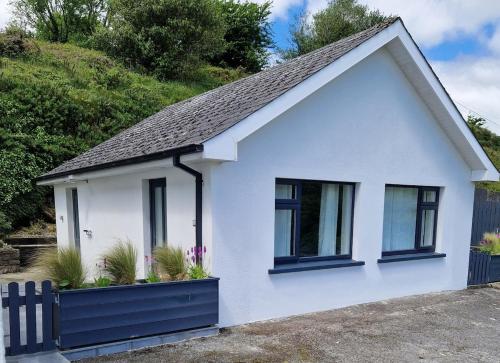 a white house with black windows and a fence at La Cabaña - Studio apartment between Leap and Rosscarbery in Leap