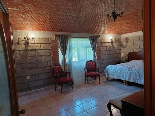 a bedroom with a bed and two chairs at Villa Colibri in Tequisquiapan