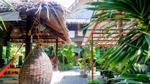a garden with a straw umbrella and some plants at Ilakai Hostel in General Luna