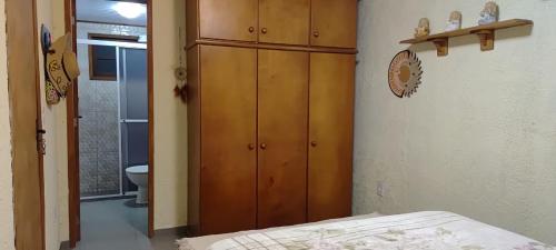 a bedroom with a wooden cabinet and a bed at Los Soles Hermenegildo in Santa Vitória do Palmar